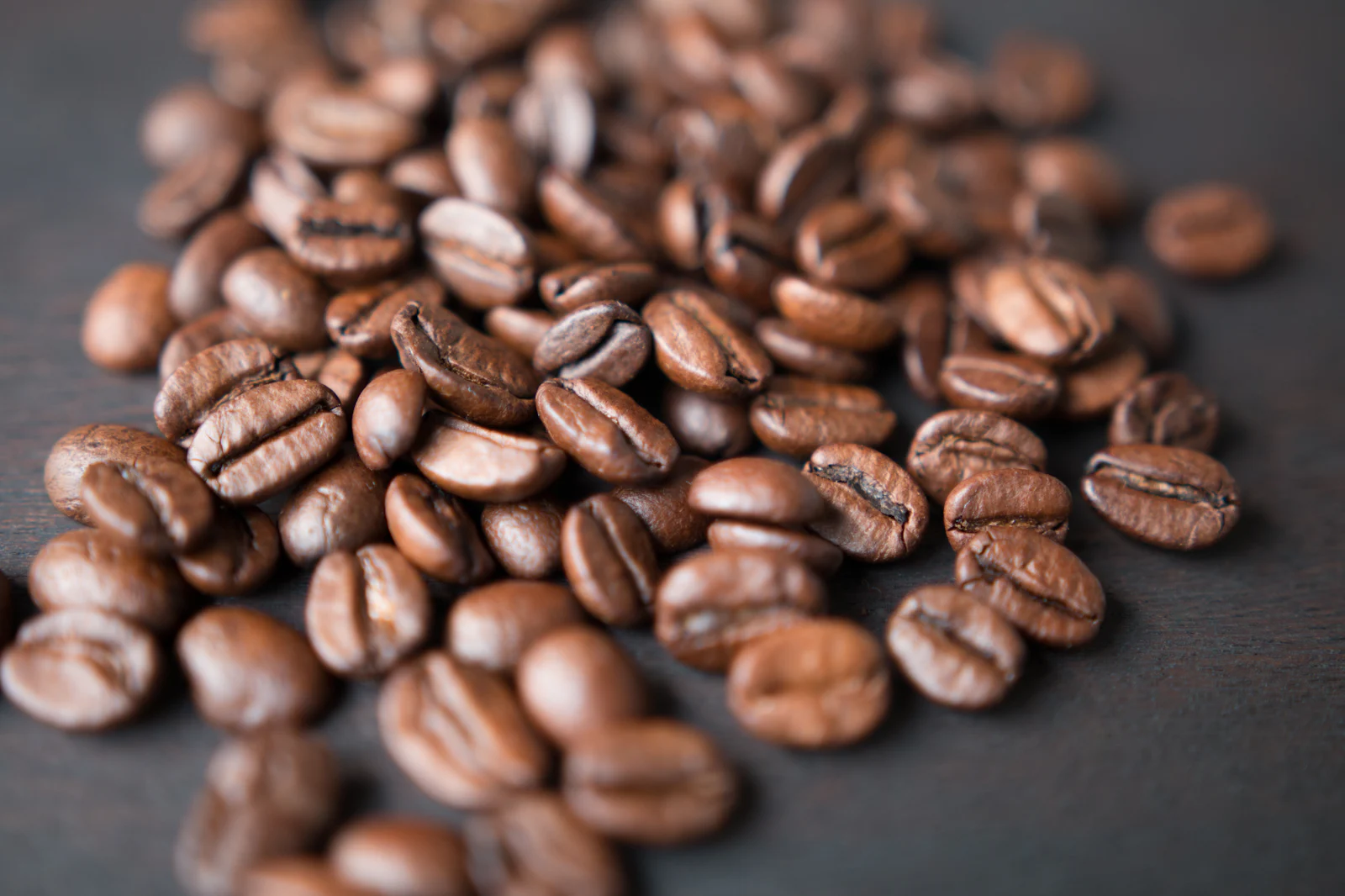 Granos de café tostados sobre una superficie gris